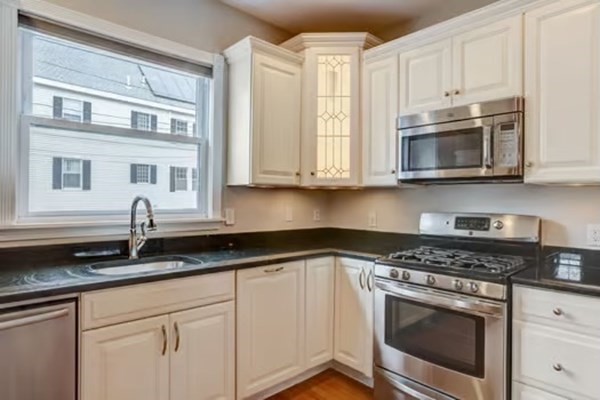 42 Lagrange Street, Unit 1 Boston, MA 02132 - Photo 10 of 29 a kitchen with granite countertop white cabinets stainless steel appliances and a sink