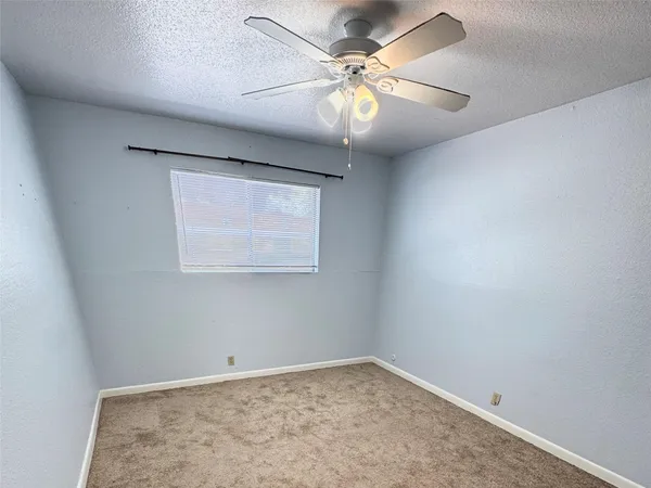 an empty room with a chandelier fan and windows