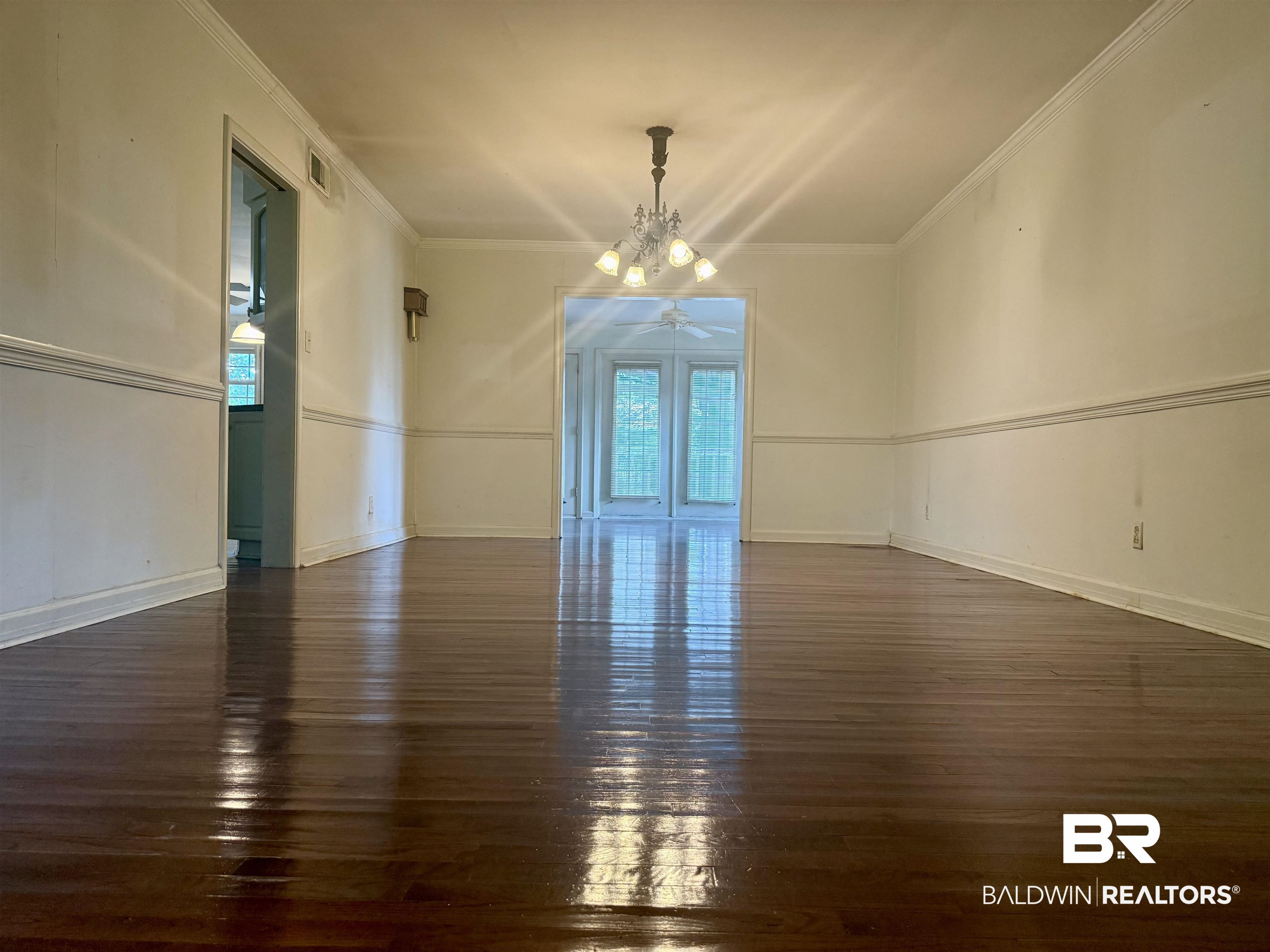 1412 Poplar Avenue Brewton, AL 36426 - Photo 7 of 32 Unfurnished room with dark wood-style flooring, a ceiling fan, a chandelier, ornamental molding, and baseboards