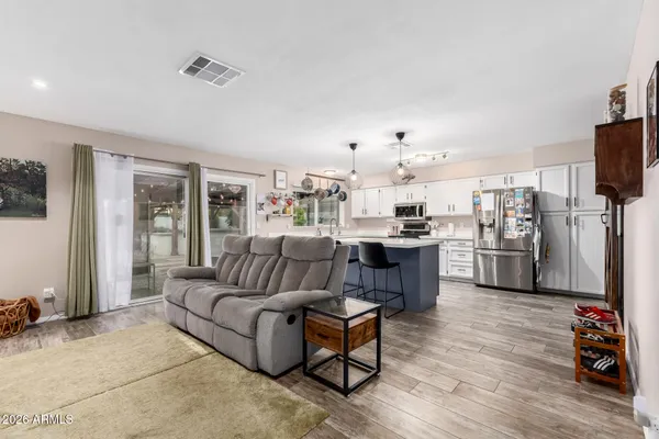 a living room with stainless steel appliances kitchen island granite countertop a couch and a view of kitchen