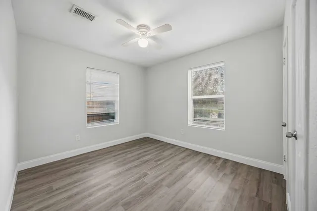 a view of an empty room with a window and wooden floor