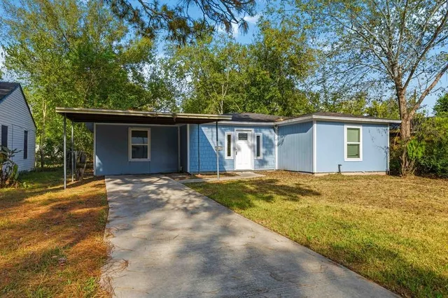 a view of a house with a yard and large tree