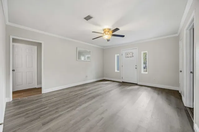 an empty room with wooden floor and windows