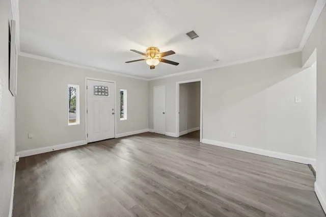 an empty room with wooden floor and chandelier fan