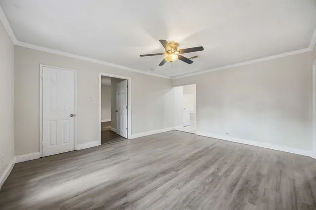 an empty room with wooden floor and ceiling fan