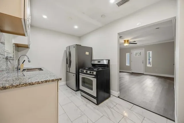 a kitchen with stainless steel appliances granite countertop a refrigerator a sink a stove and oven