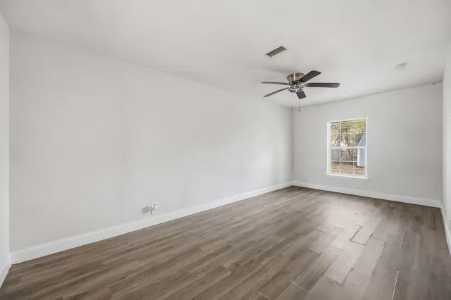 a view of an empty room with a window and wooden floor