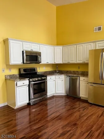 a kitchen with granite countertop a refrigerator stove and wooden floor