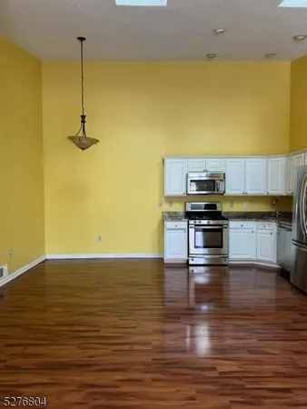 a kitchen with stainless steel appliances wooden floor and a refrigerator