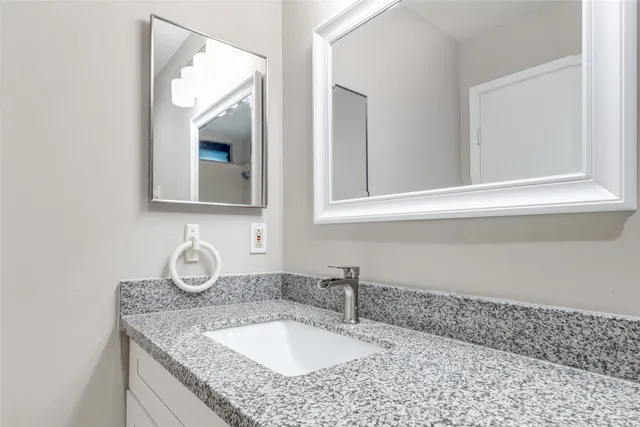a bathroom with a granite countertop sink and a mirror