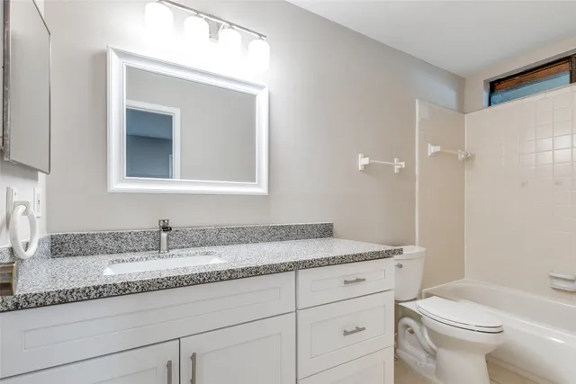a bathroom with a granite countertop sink a toilet and a mirror