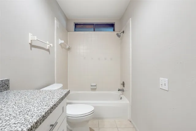 a bathroom with a granite countertop toilet a sink and bathtub