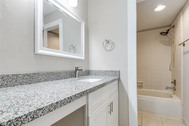 a bathroom with a granite countertop sink a mirror and a bathtub