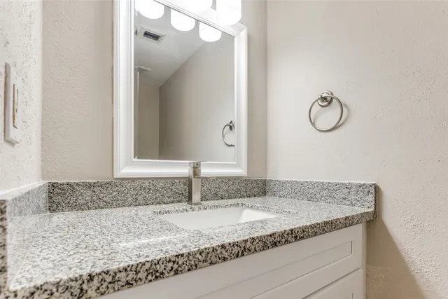a bathroom with a granite countertop sink and a mirror