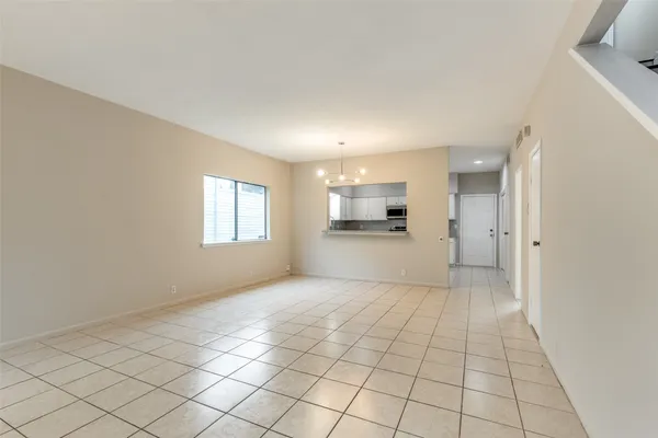 a view of an empty room and a kitchen