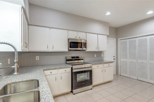 a kitchen with granite countertop white cabinets and stainless steel appliances