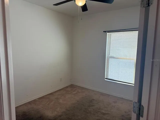 an empty room with a window and a fan