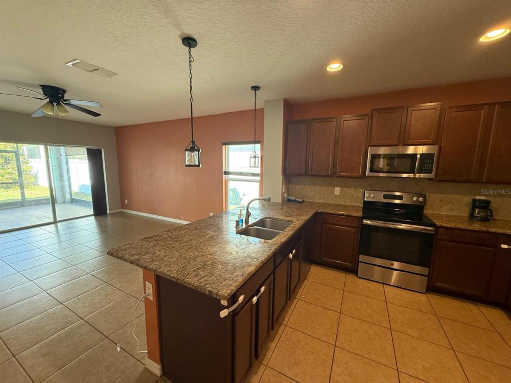 622 Samuel Place Davenport, FL 33837 - Photo 24 of 64 a kitchen with a stove a sink and a refrigerator