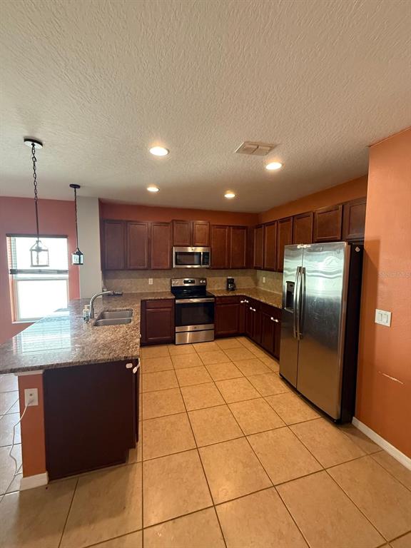 622 Samuel Place Davenport, FL 33837 - Photo 26 of 64 a kitchen with stainless steel appliances granite countertop a refrigerator and a sink