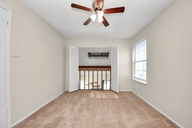 an empty room with windows and ceiling fan