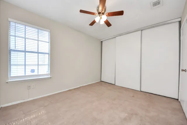 an empty room with windows and fan