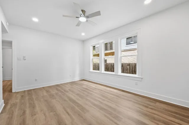 a view of an empty room with a window and wooden floor
