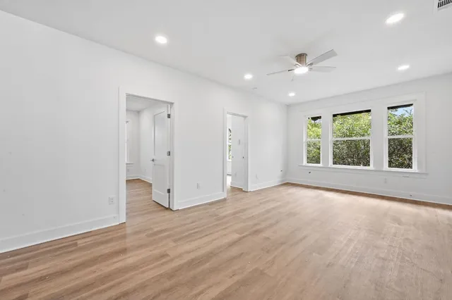 a view of an empty room with a window and wooden floor