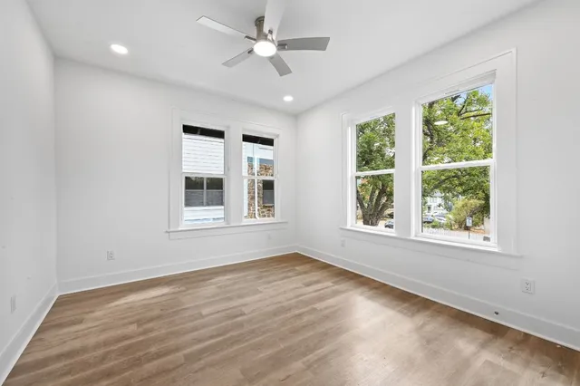 a view of an empty room with a window and wooden floor