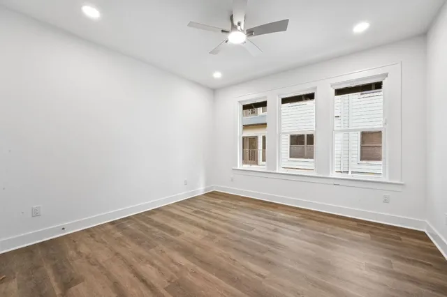 a view of an empty room with a window and wooden floor