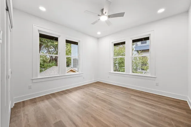 an empty room with wooden floor chandelier and windows