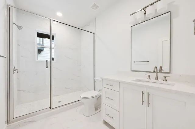 a bathroom with a double vanity sink toilet mirror and shower