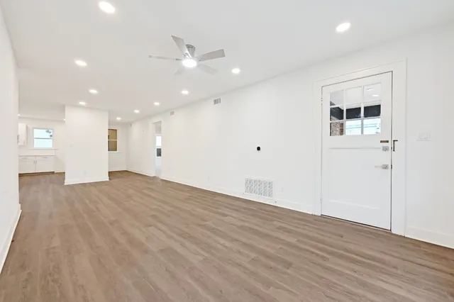 an empty room with wooden floor and kitchen view