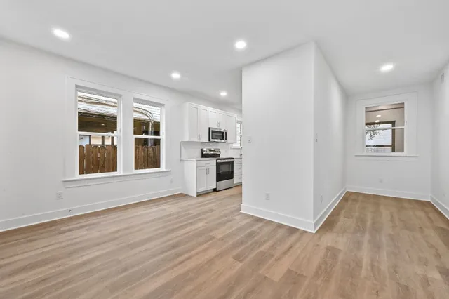 an empty room with wooden floor and windows