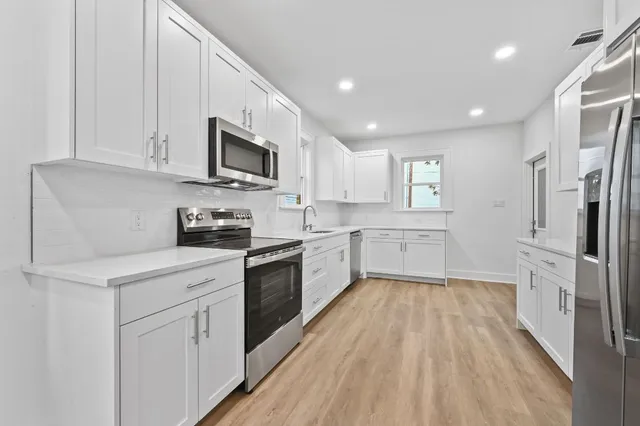 a kitchen with white cabinets and stainless steel appliances