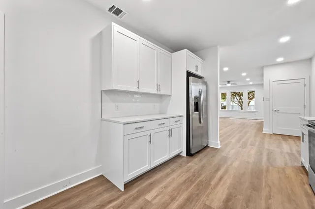 a kitchen with white cabinets and wooden floor