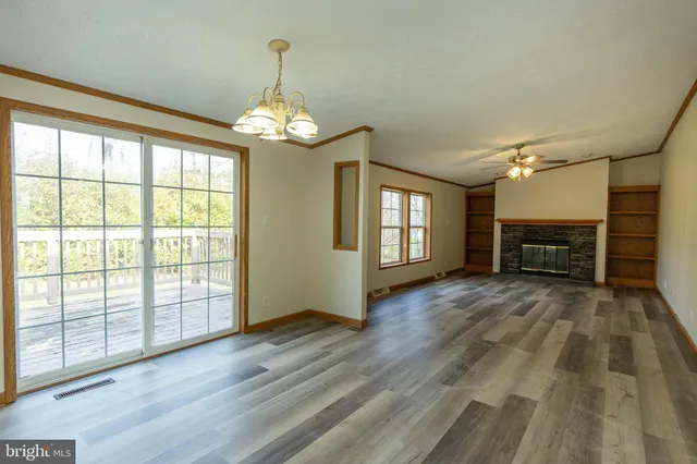 an empty room with wooden floor fireplace and windows