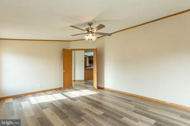 a view of a big room with wooden floor and a chandelier fan