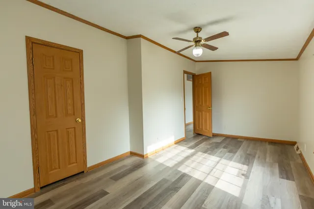 a view of empty room with wooden floor and fan