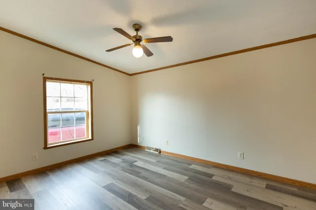 an empty room with wooden floor fan and windows