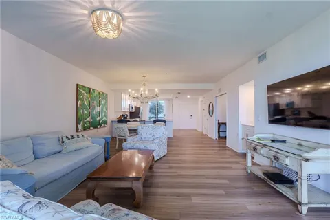a living room with furniture flat screen tv and kitchen view