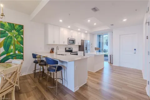 a living room with stainless steel appliances kitchen island a table and chair