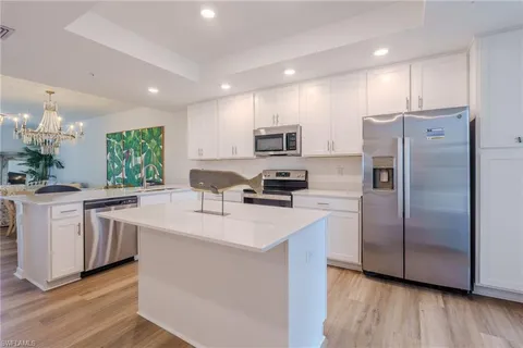 a kitchen with kitchen island granite countertop a center island stainless steel appliances a sink a refrigerator and cabinets