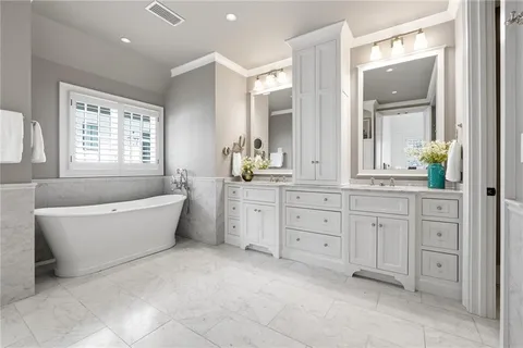 a spacious bathroom with double vanity a mirror a bathtub and a window