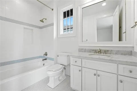 a bathroom with a granite countertop sink toilet a large mirror a bathtub and shower
