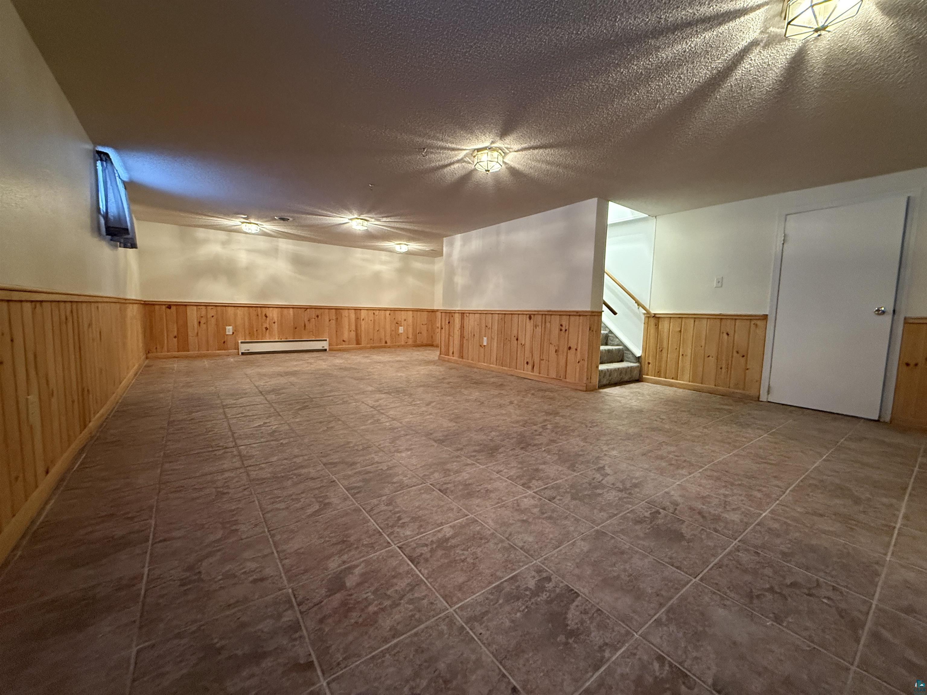 1321 South 13th Street Virginia, MN 55792 - Photo 20 of 33 Additional living space with a textured ceiling, a wainscoted wall, a baseboard heating unit, and wood walls