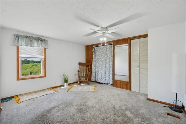 a view of a livingroom with a staircase a ceiling fan and a window