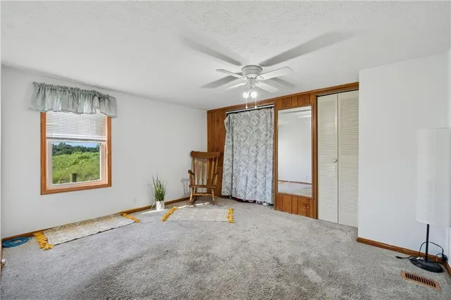 a view of a livingroom with a staircase a ceiling fan and a window