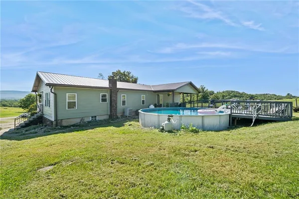 a view of a house with pool and chairs in front of house