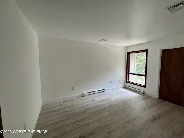 an empty room with wooden floor and windows