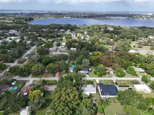 an aerial view of residential houses with outdoor space and trees